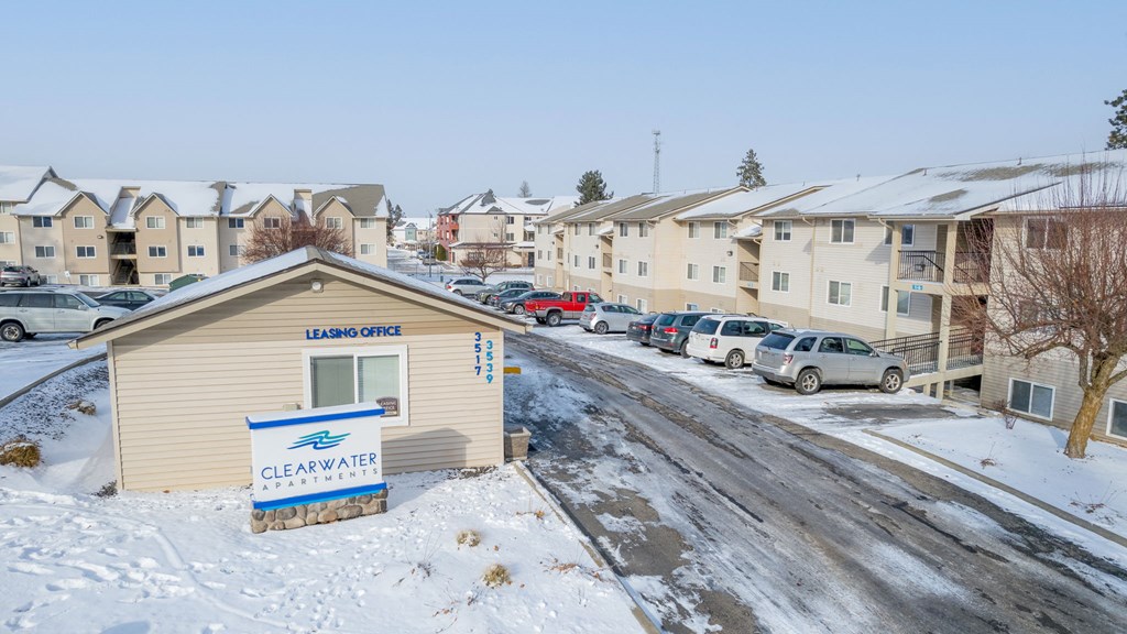 Outside the community on a snowy day. The leasing office is behind a sign that says Clearwater Apartments.at Clearwater, Post Falls, ID