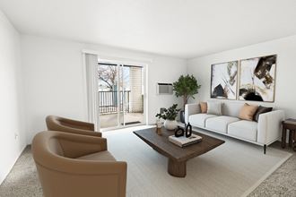 A bright living room with white walls and two glass sliding doors to a private balcony. Staged with a couch, 2 chairs, table and plant.at North Pointe, Post Falls, 83854