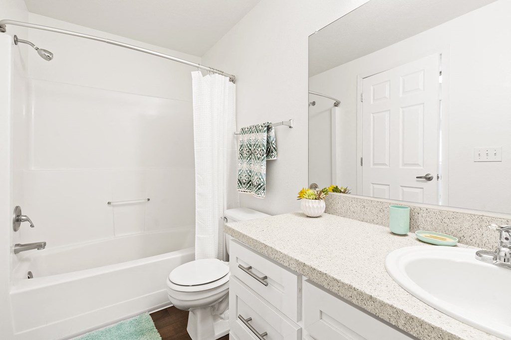 White bathroom with new white cabinets, large mirror, white toilet and full size bathtub.at North Pointe, Post Falls, 83854