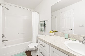 White bathroom with new white cabinets, large mirror, white toilet and full size bathtub. - Photo Gallery 27