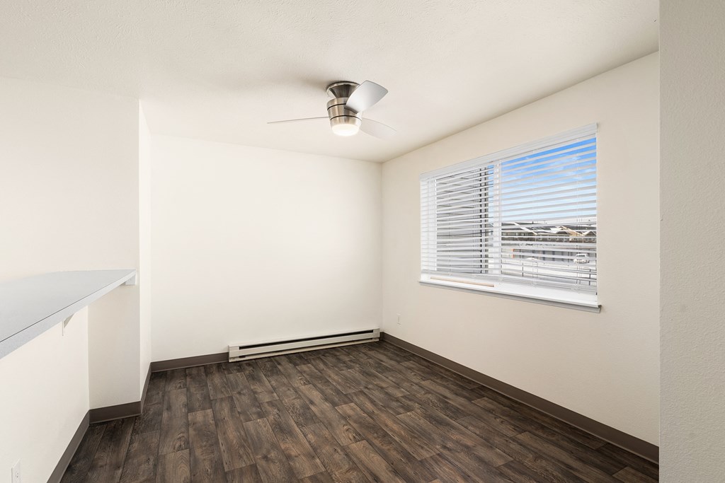A bright dining room with a large window looking out to blue skies. Hardwood floors and bar counter with a ceiling fan above.at Clearwater, Idaho, 83854