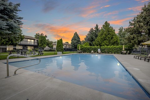 A large swimming pool surrounded by trees and a building in the background.