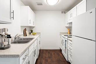 A galley-style kitchen with white cabinets and appliances and new countertops.at North Pointe, Post Falls Idaho