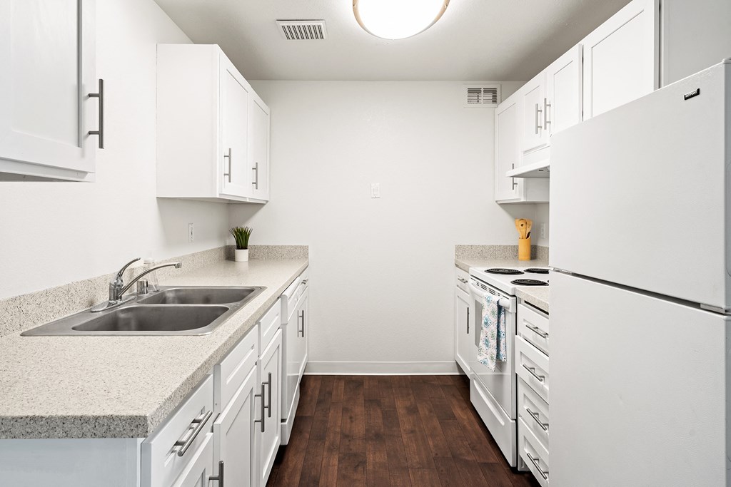 Bright white kitchen with dark faux wood flooring, new cabinets and countertops.at North Pointe, Post Falls, ID