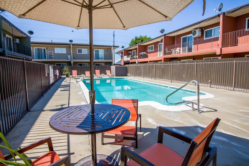 a pool with a table and chairs next to a resort style pool at Ella 1711 Apartments, Woodland, CA 95695