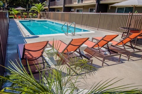 a pool with a poolside deck with chairs and a swimming pool at Ella 1711 Apartments, Woodland, CA