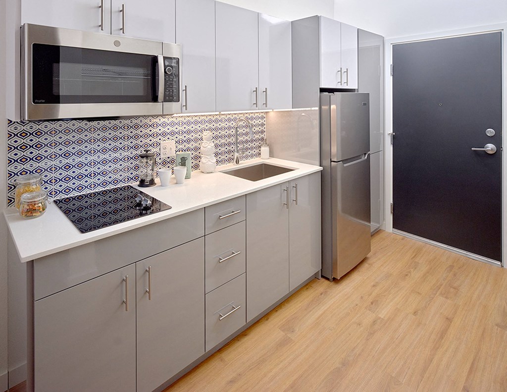 a kitchen with white cabinets and a sink and a refrigerator at Enve, Seattle