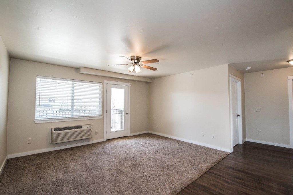 an empty living room with a ceiling fan and a window