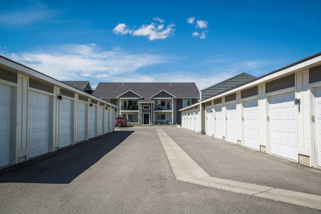 a row of garages with white doors and a house in the background at Madison Park, Bozeman, MT, 59718