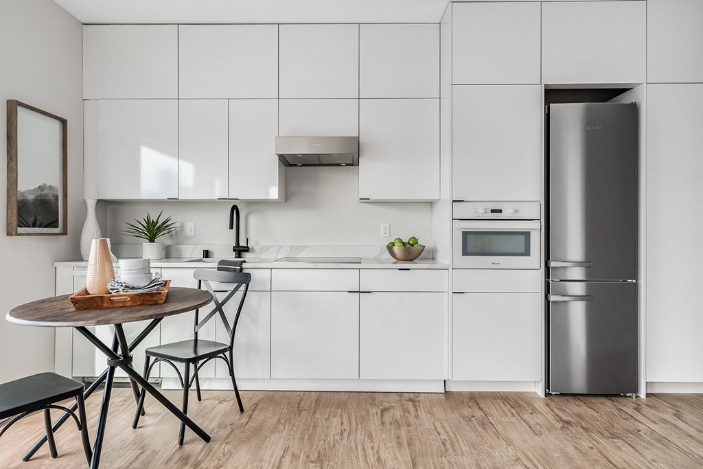 a white kitchen with a small table and a refrigerator  at Oslo, Seattle, 98102