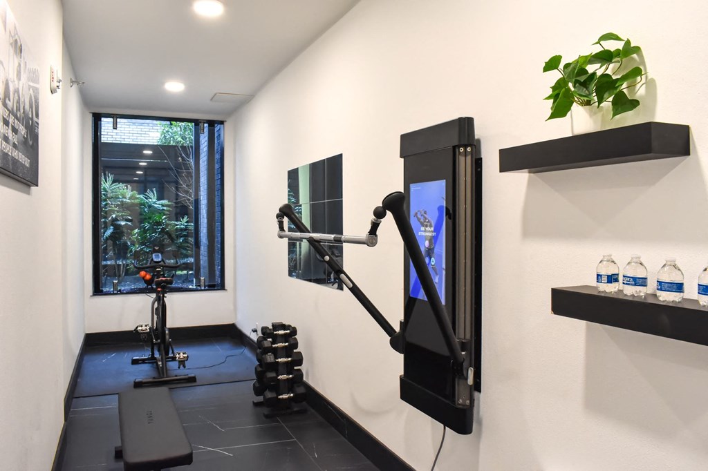 a gym with a treadmill and a tv in a room with a window  at Oslo, Seattle, Washington