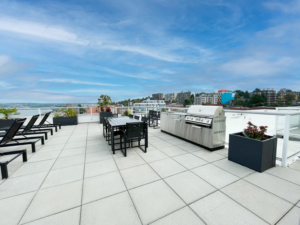 a rooftop patio with a grill and a city in the background  at Oslo, Seattle, Washington