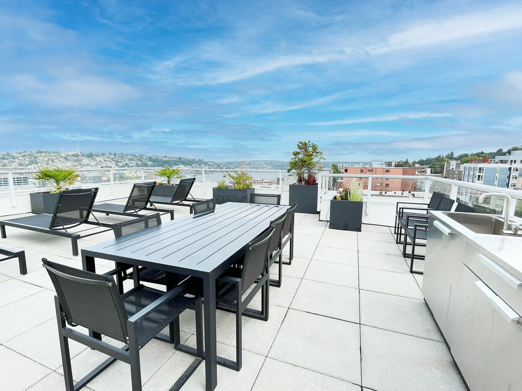 a patio with a table and chairs on a roof  at Oslo, Seattle, WA, 98102