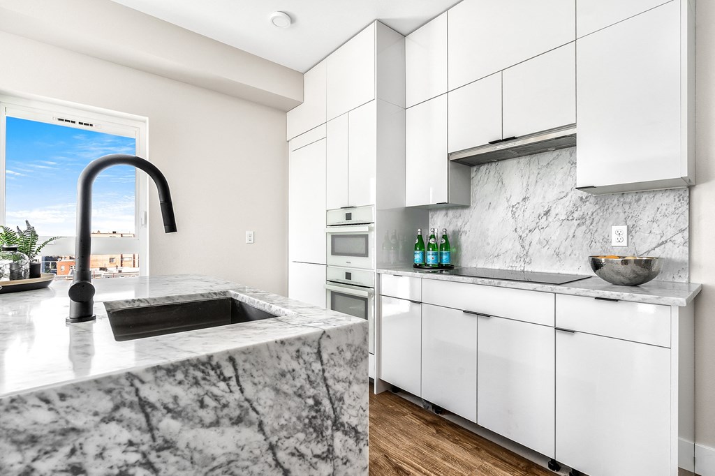 a kitchen with white cabinets and marble counter tops and a sink  at Oslo, Seattle, 98102