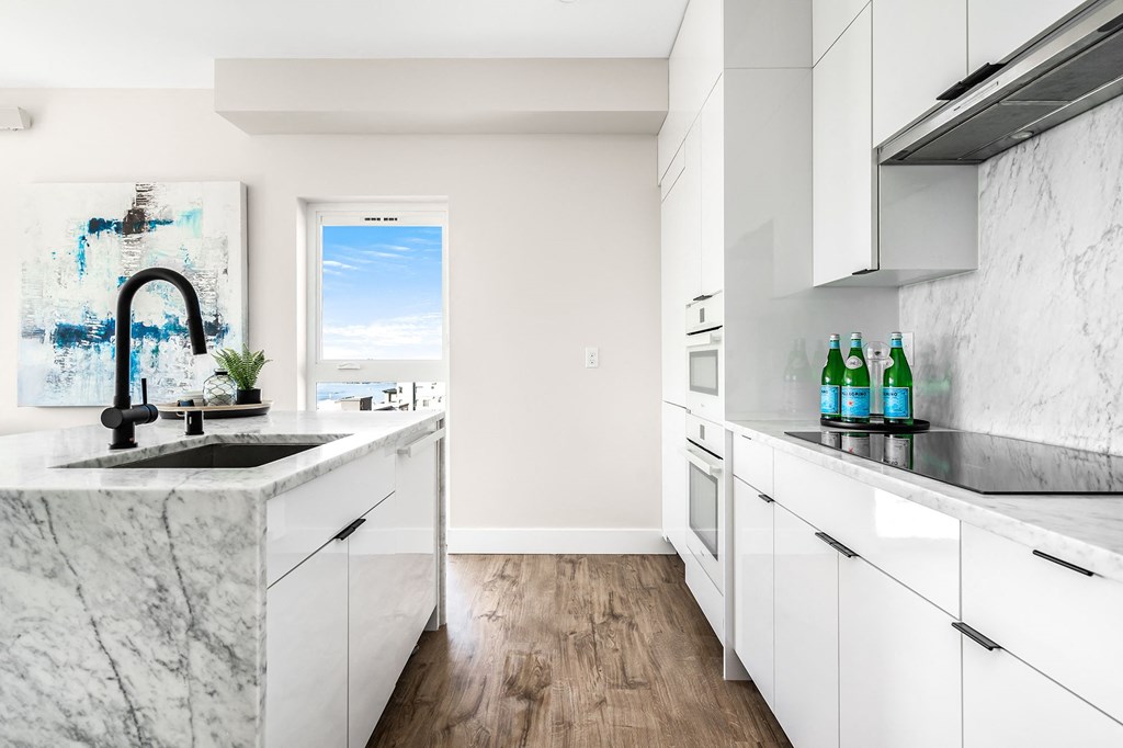 a kitchen with marble counter tops and white cabinets  at Oslo, Seattle, 98102