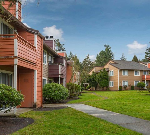 a walkway between two apartment buildings with grass and trees at Quartz Creek, Mountlake Terrace, WA, 98043