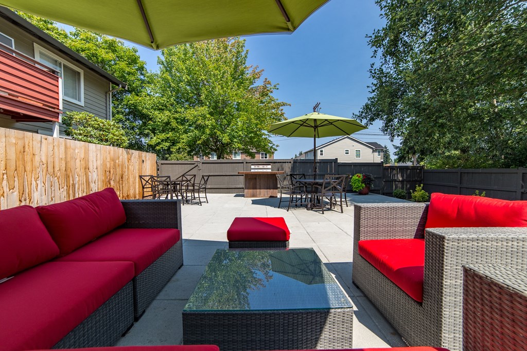 a backyard patio with red couches and a glass table at Quartz Creek, Mountlake Terrace, WA, 98043