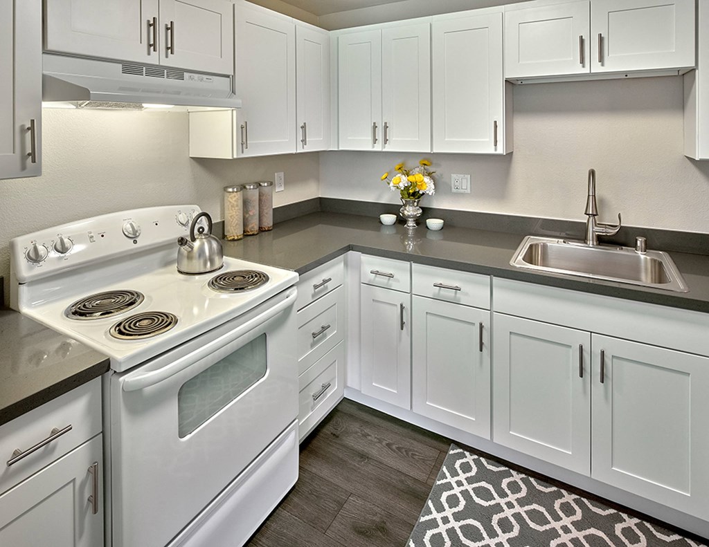 a kitchen with white cabinets and a white stove and sink a kitchen with white cabinets and a white stove and sink at Quartz Creek, Mountlake Terrace