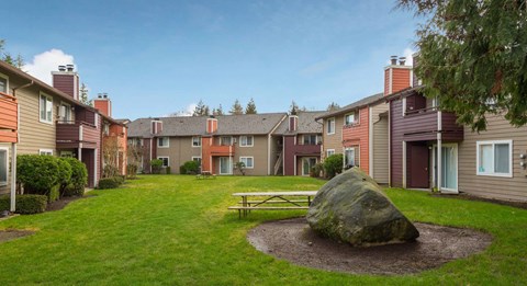 a park with a picnic table and a rock in the grass at Quartz Creek, Mountlake Terrace, Washington