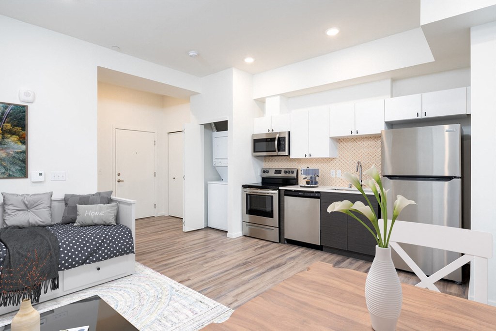 a living room with a couch and a kitchen with stainless steel appliances  at The Loop at Green Lake, Seattle, Washington