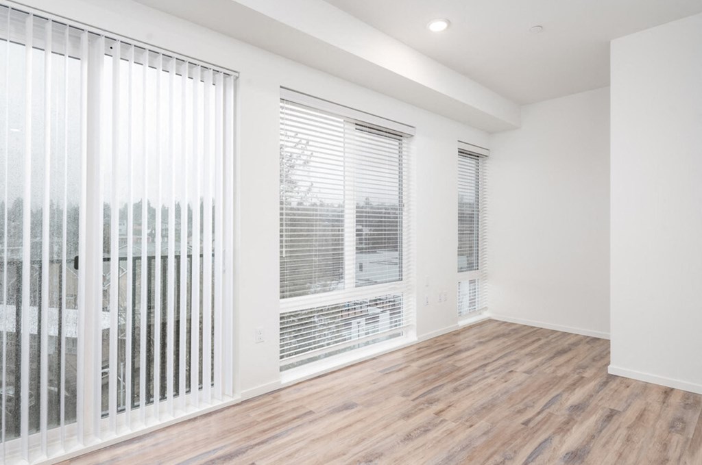 an empty living room with large windows and a wood floor at The Loop at Green Lake, Washington