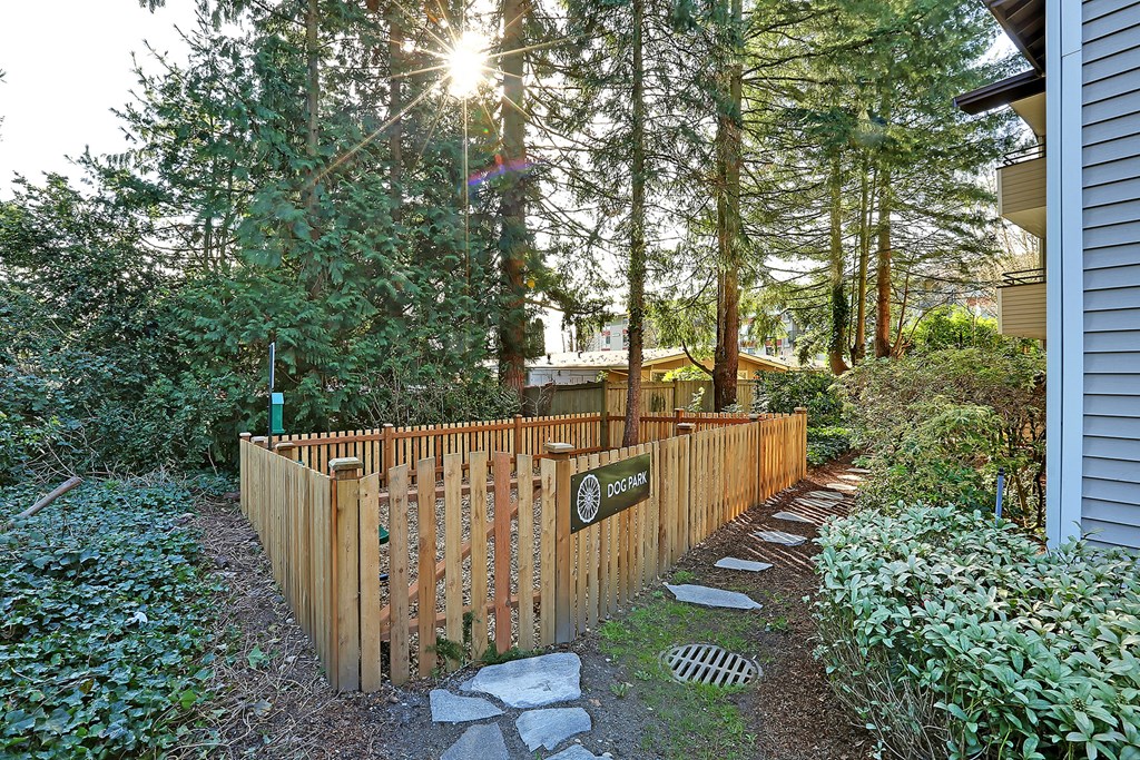 a wooden fence in front of a house with trees  at Townside Flats, Redmond, 98052