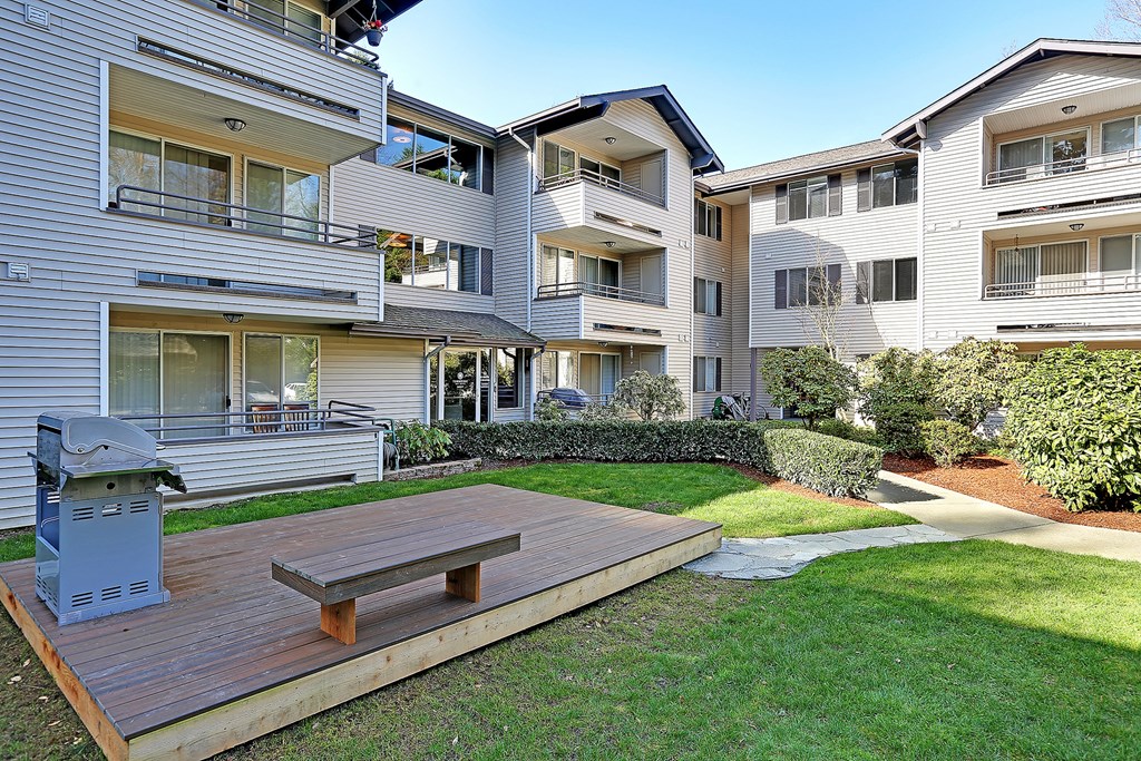 a backyard with a picnic table in front of an apartment building  at Townside Flats, Redmond, WA