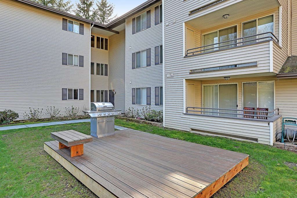 the backyard of an apartment building with a wooden deck and a fire pit  at Townside Flats, Redmond