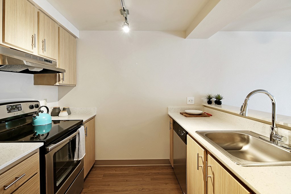 a kitchen with wooden cabinets and a sink and a stove  at Townside Flats, Redmond, 98052