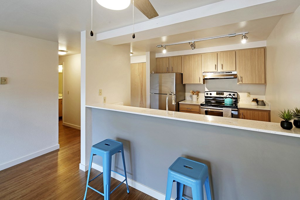 a kitchen with two blue stools in front of a bar with a counter top  at Townside Flats, Redmond