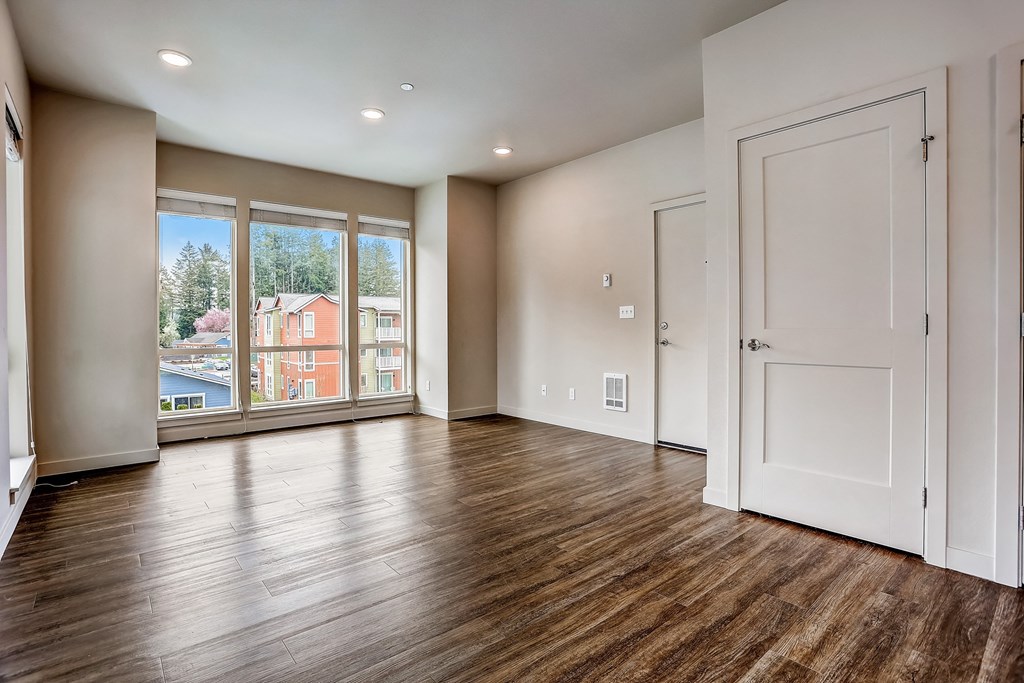an empty living room with a large window and wooden floors at Woodcreek, Poulsbo