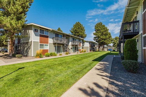 A row of apartment buildings with a sidewalk in front.