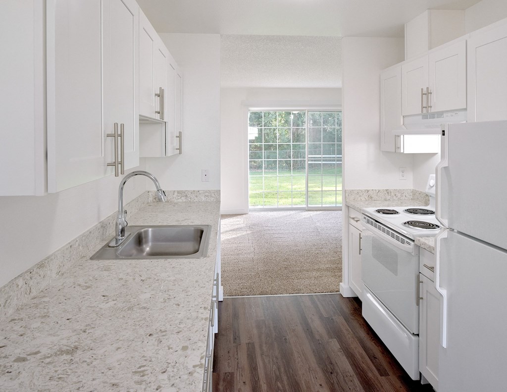 an empty kitchen with white cabinets and white appliances and a window at Woodcreek, Washington