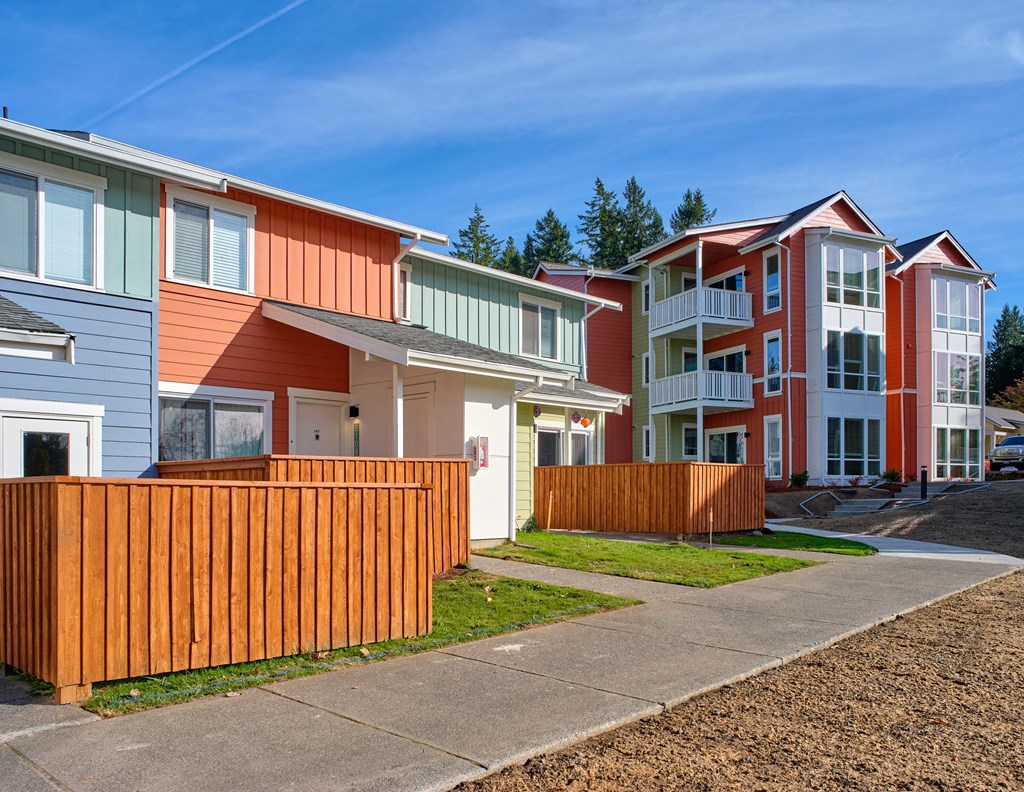 a row of colorful homes in front of a sidewalk at Woodcreek, Poulsbo