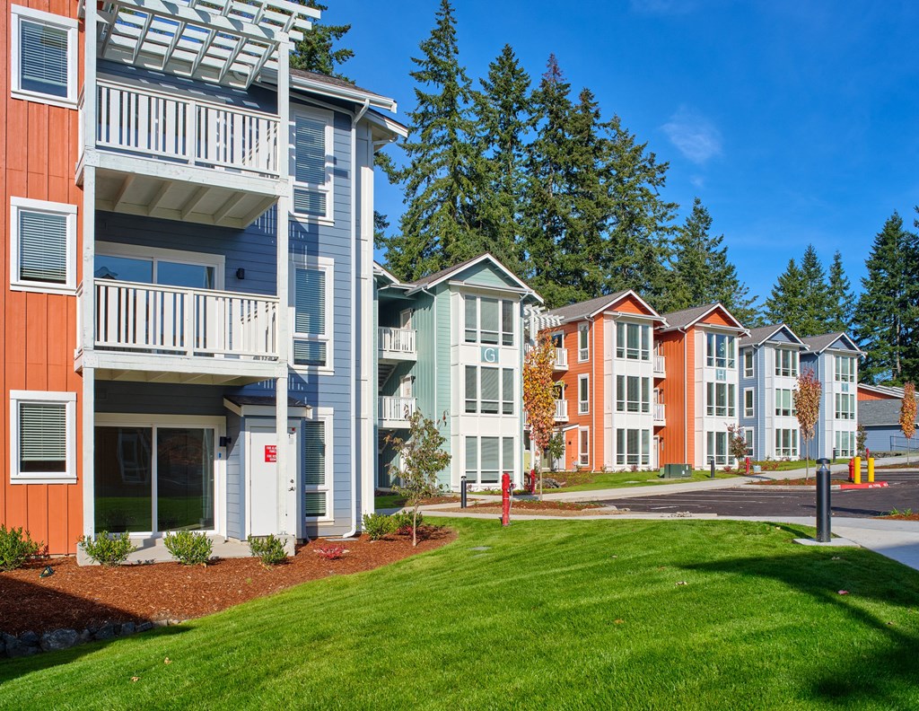 an exterior view of a row of apartment buildings with green grass at Woodcreek, Poulsbo Washington