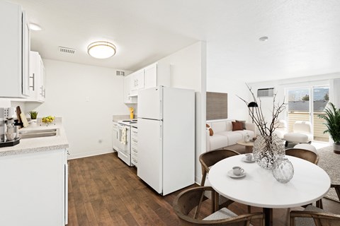 A kitchen and dining area looking into living room filled with natural light. Staged with dining set and living room furniture.at North Pointe, Idaho, 83854