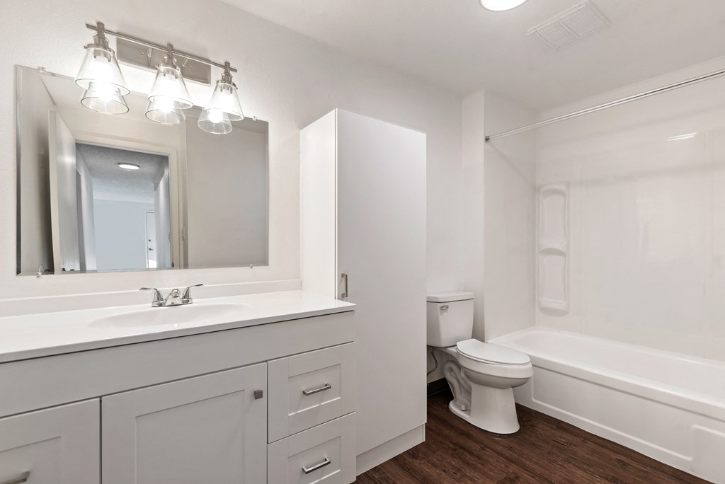 a bathroom with white cabinets and a toilet and a sink