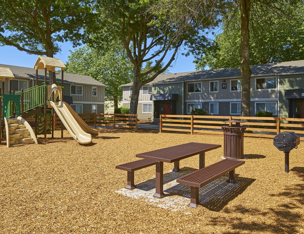 a playground with a slide and a picnic table in front of apartments  at Woodhaven, Everett, Washington