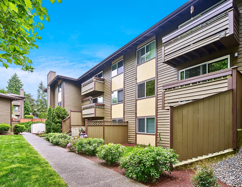 Exterior view of personal patios or balconies, manicured grounds and building, and blue skies in the background at Heritage Grove, Renton, WA.