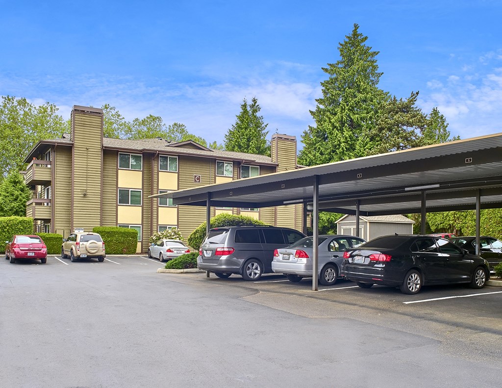 a parking lot with covered parking in front of Heritage Grove Apartments in Renton, WA