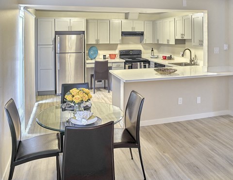 a kitchen with white cabinets and a white counter top and a glass table with black chairs  at 3030 Lake City, Seattle, WA