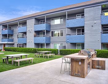 an exterior view of an apartment building with picnic tables and a grill  at 3030 Lake City, Seattle, WA