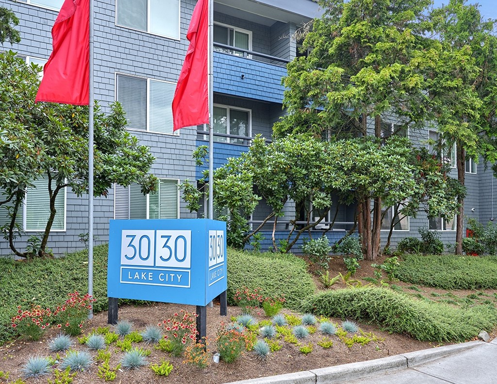 a large blue apartment building with two red flags in front of it  at 3030 Lake City, Seattle, Washington