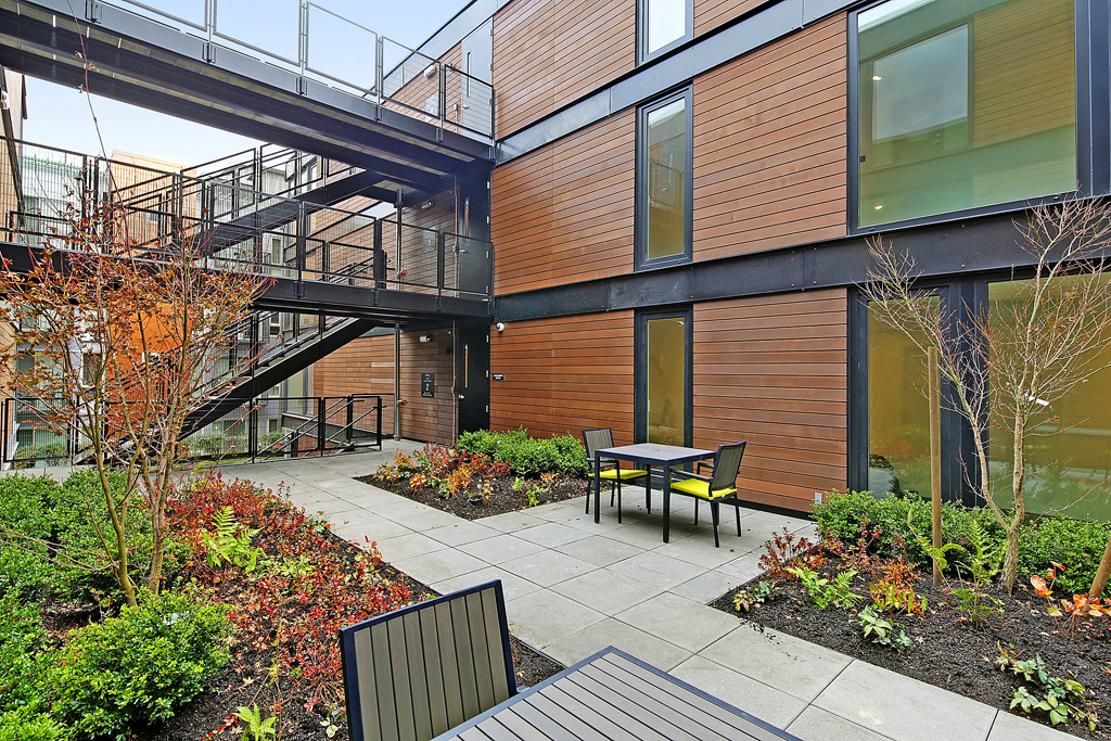 Exterior view of the community. Well maintained landscaping with pathways to building. Small seating area.at 19th & Mercer, Washington, 98112