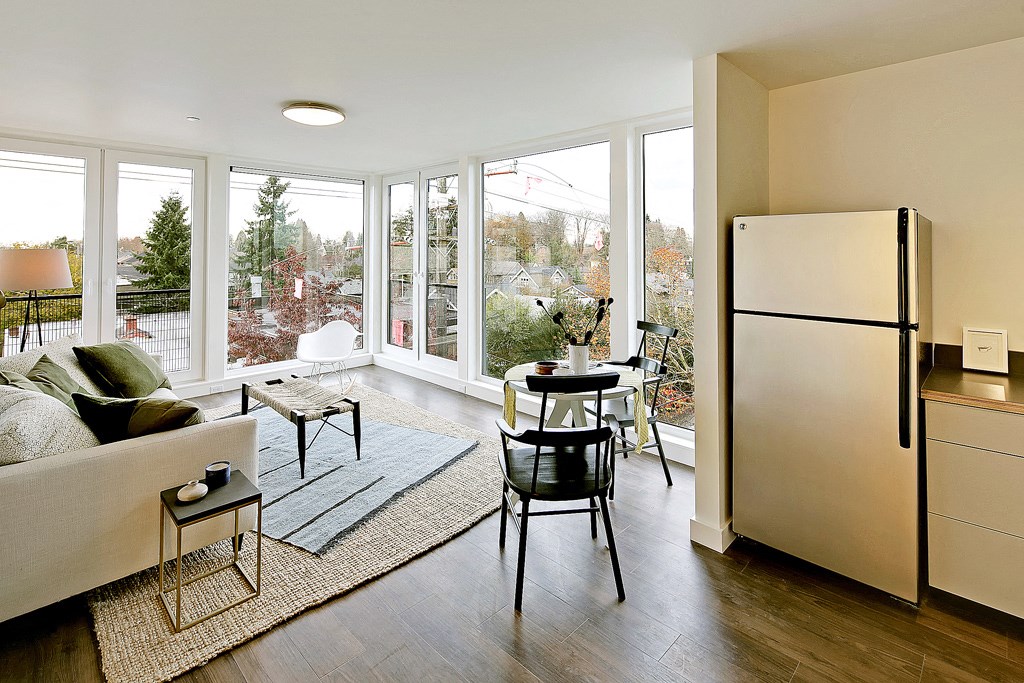Kitchen & Living Area Living room with floor to ceiling windows with city and tree views. Staged with a couch, coffee table, rug and chair.at 19th & Mercer, Seattle Washington