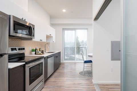 a kitchen with stainless steel appliances and a door to a balcony