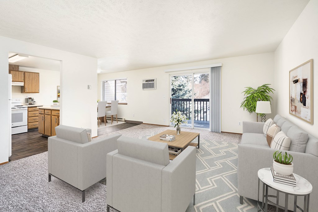Spacious living room with glass sliding doors to private covered balcony. Living room staged with a couch, 2 chairs, and a coffee table. at Clearwater, Post Falls, ID 83854