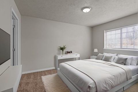 A bedroom with a large bed and a nightstand with a plant on it.