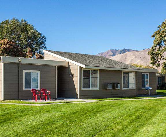 Exterior view of building with views of mountains in distance and grassy area.at Park View Apartments, Wenatchee, WA 98801