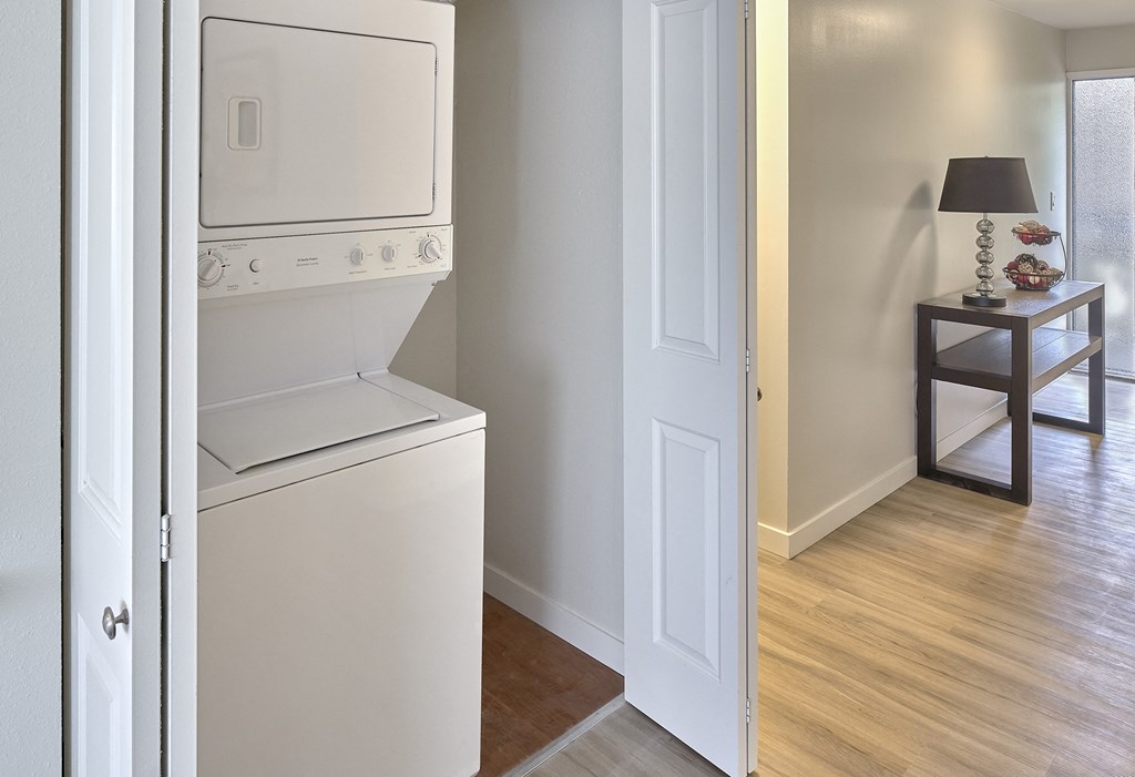 Wood floor hallway with a washer and dryer closet with open bifold doors. Extra storage space to the right of the machines. at 3030 Lake City, Seattle, 98125